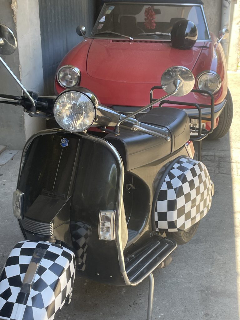 Eine freche restaurierte schwarze Vespa mit schwarz-weiß karierten Blechen.