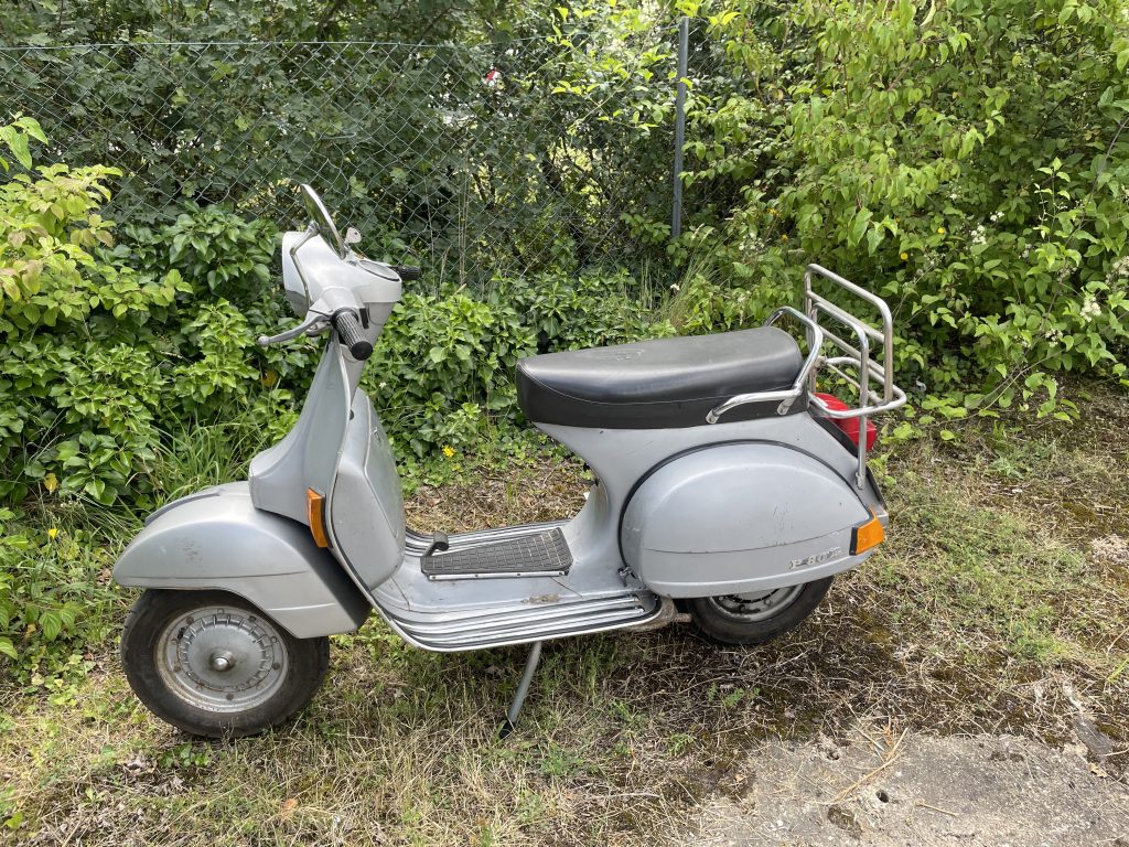 Hellblaue restaurierte Vespa im Grün