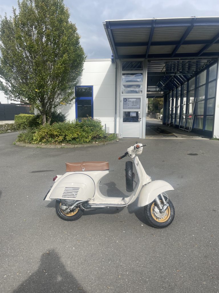 Weiße schöne Vespa vor einem Gebäude.